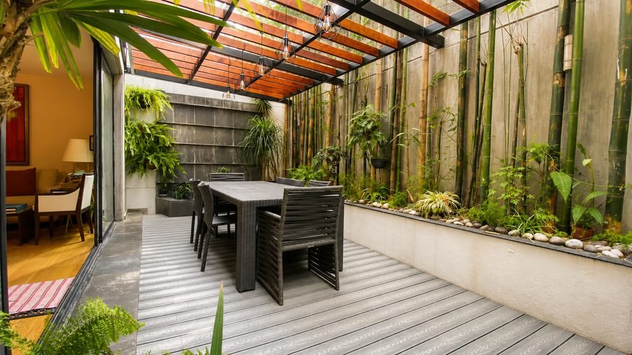 Terraza techada con jardín de bambú y comedor exterior